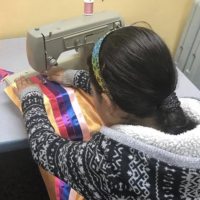 Student sewing ribbons on skirt
